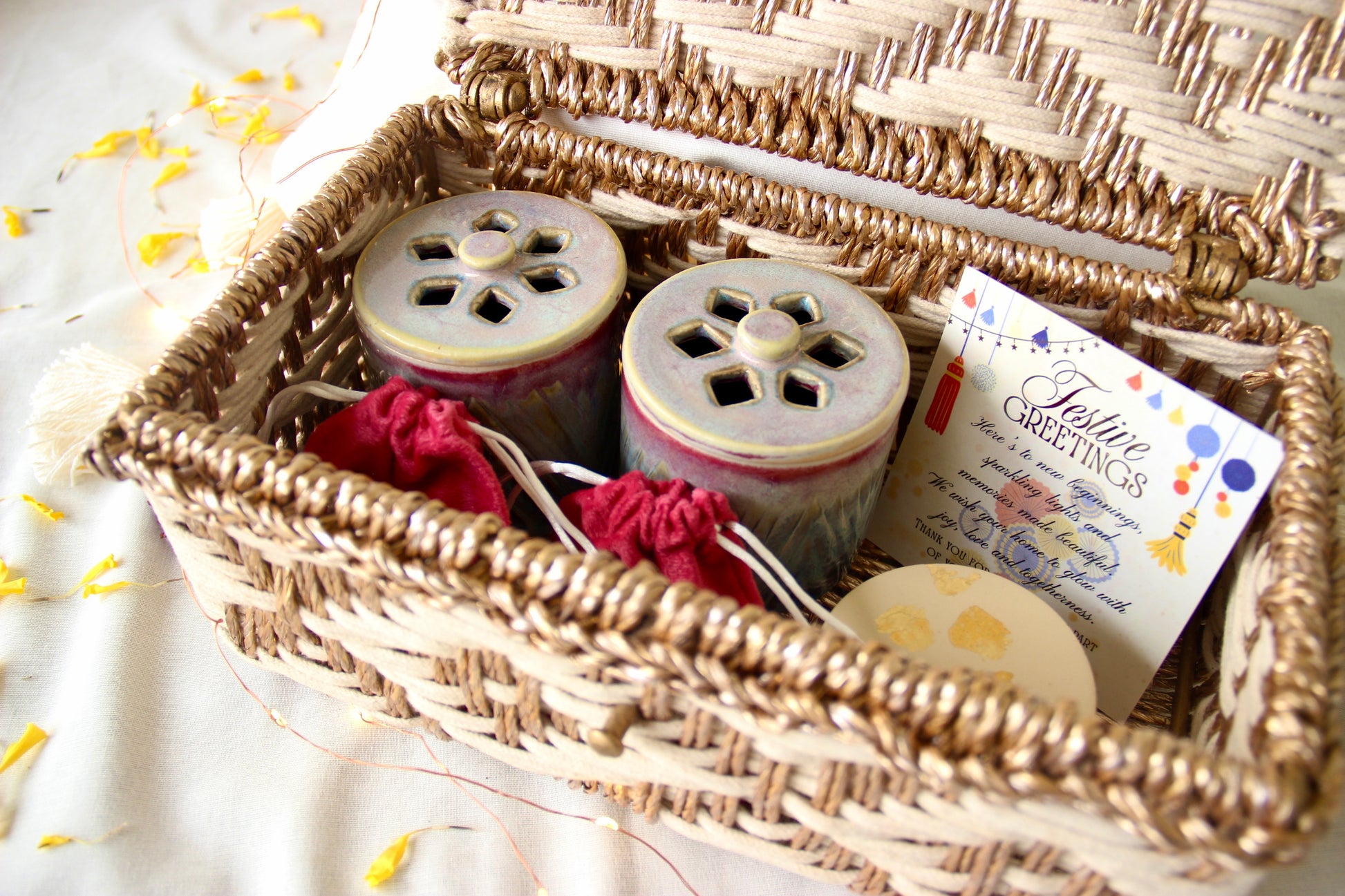 Wicker basket with decorative items including jars, a card, and a candle on a light background.