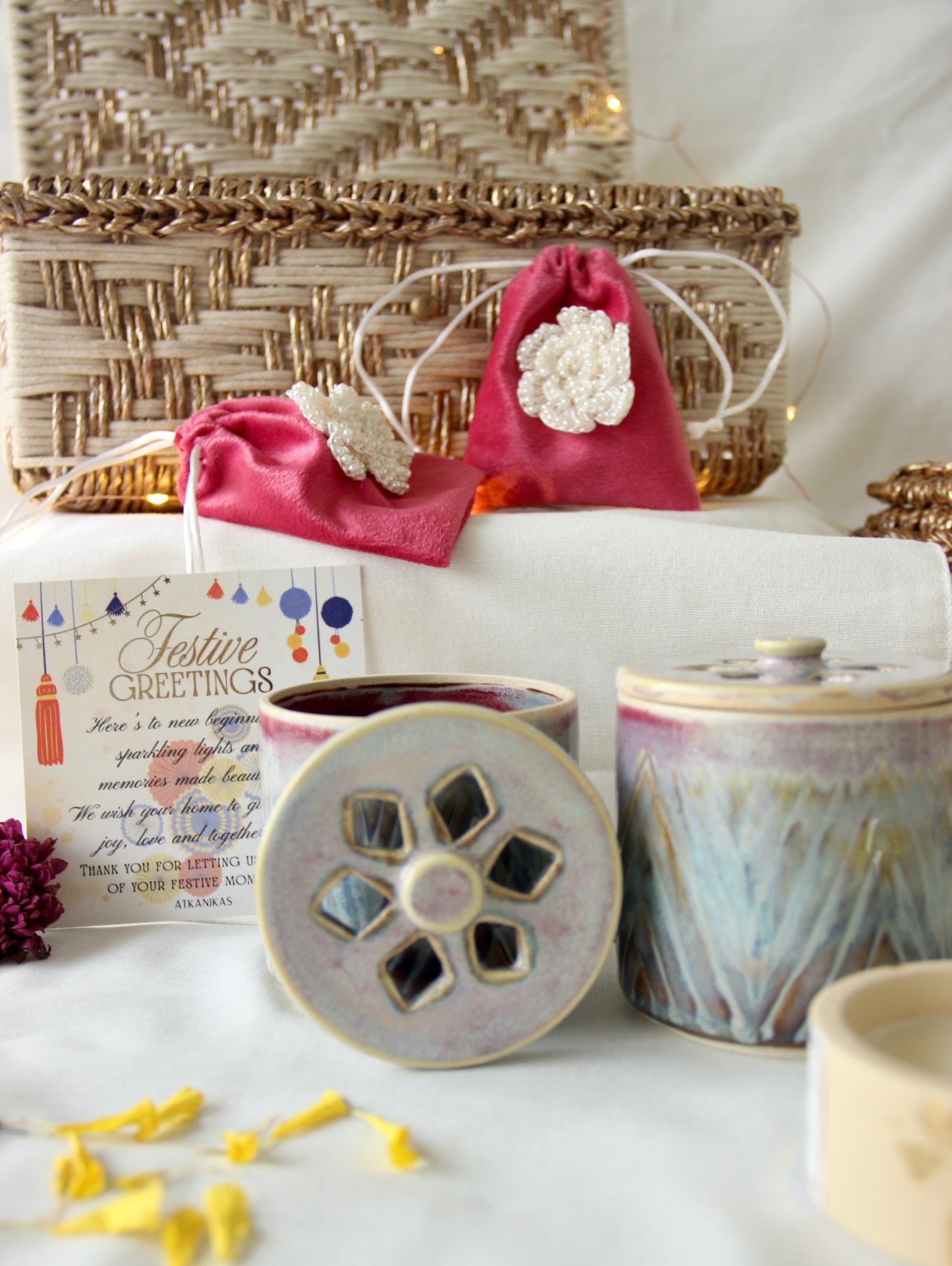 Decorative items including a pink bag with white flowers, a woven basket, and ceramic containers on a white surface.