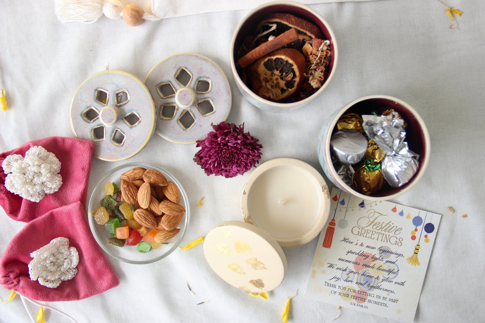 Assorted items including a bowl of dried fruits, a candle, and a card on a white surface.