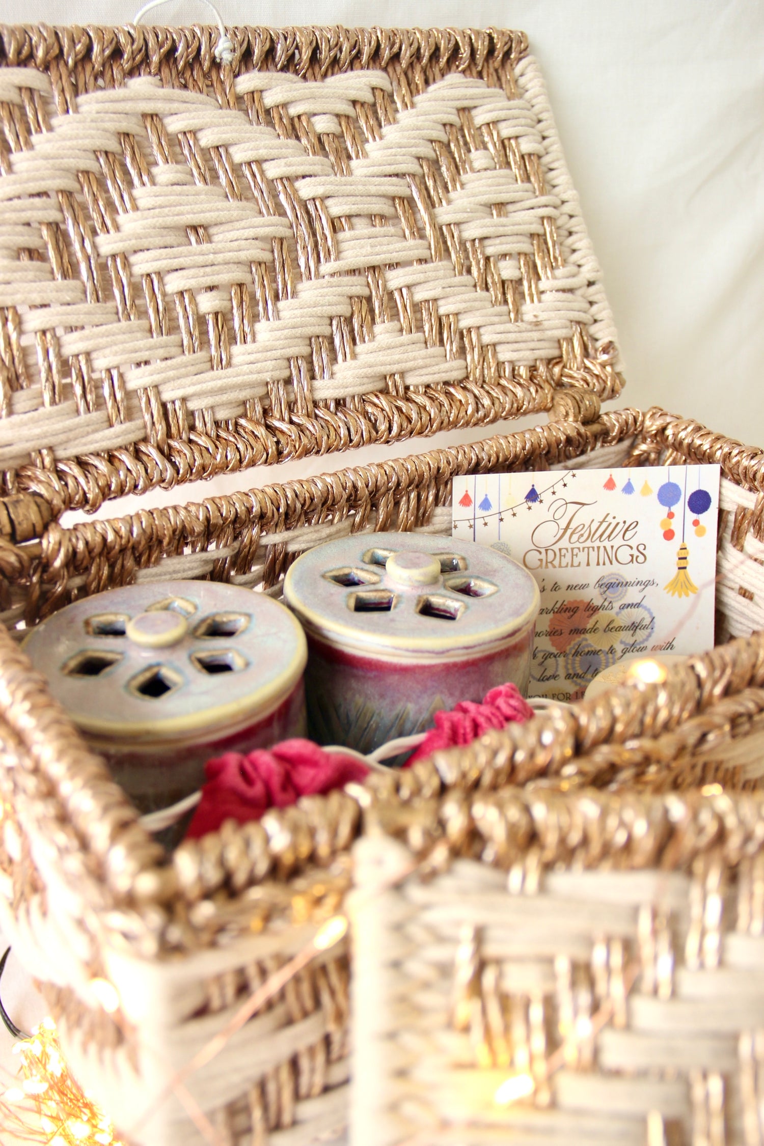 Woven basket with decorative items including candles and a card on a white background